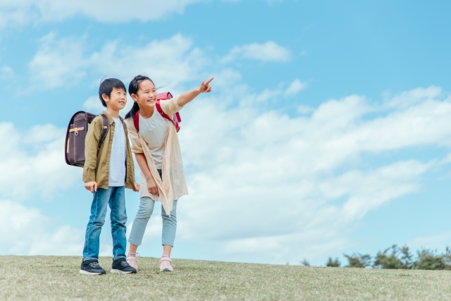 何かを見つけて指をさす小学生